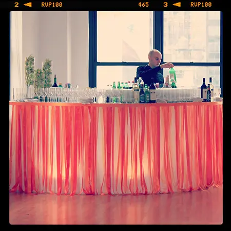 A man standing at the bar in front of a window.